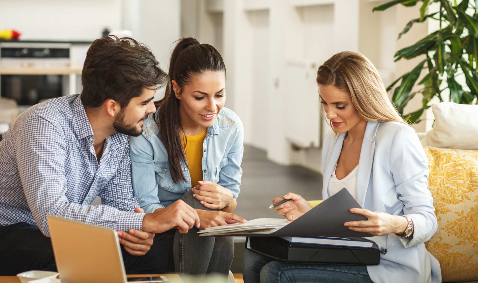 Two women and a man sitting down while reviewing paperwork in an office environment