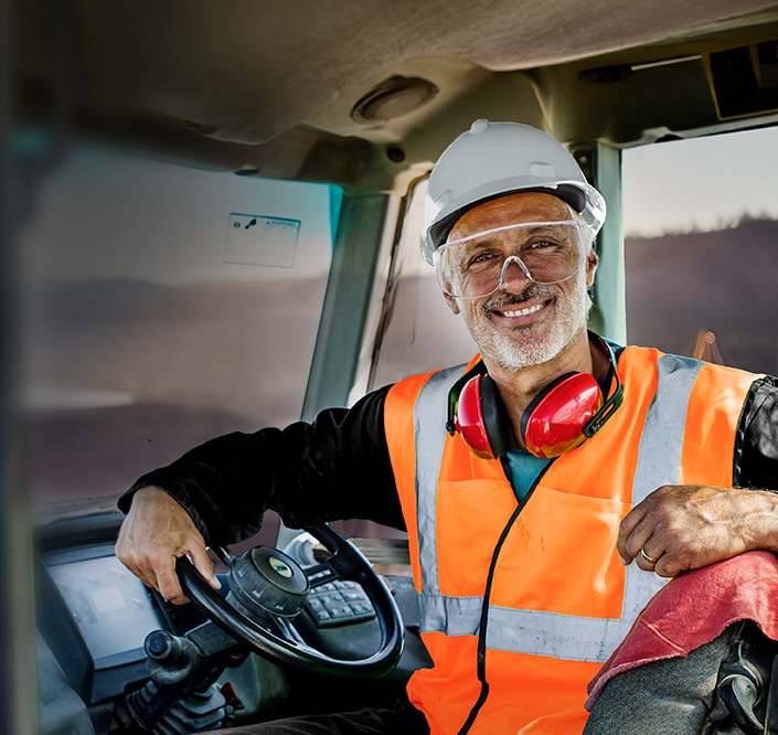 Driver with white hard hat smiling at the camera.