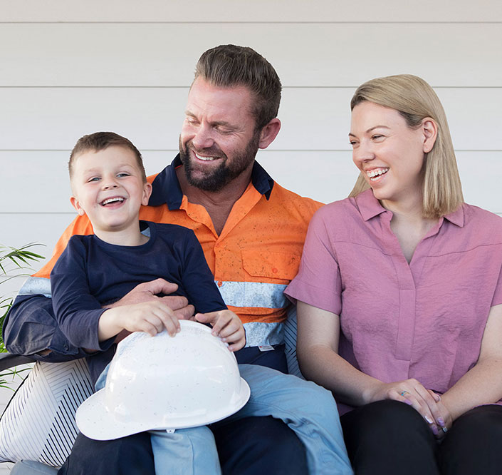 Man, woman and child sitting together smiling holding a hard hat